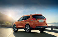 Rear view of orange X-Trail standing next to a road