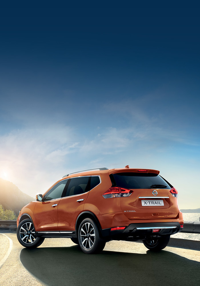 Rear view of orange X-Trail standing next to a road