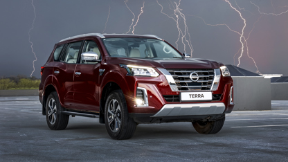 Red Nissan Terra in open field with lighting in background